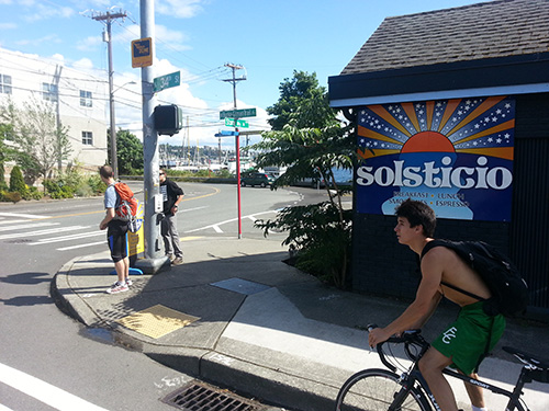 View from eastbound car lane. The trail is behind the Solsticio building, and the presence of bicyclists on both sides of it may further confuse drivers.